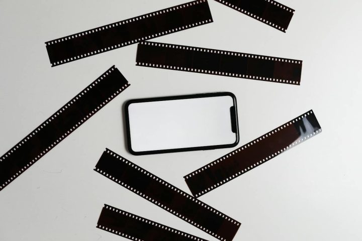 film tapes scattered on table near smartphone. digitizing 110 film negatives. digitize 110 negatives.